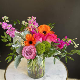 Mixed bouquet in a clear glass vase with pink roses and orange gerbera daisies