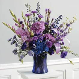 Purple and blue floral arrangement in a dark blue vase