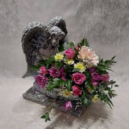 Pink and white mixed bouquet arranged around a stone angel statue