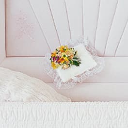Small floral pillow with lace trim on a pink bedspread
