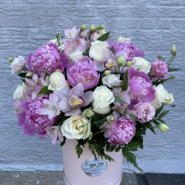 Pink and white mixed flower arrangement in a round box