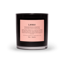 Black scented candle in a glass jar with a pink label