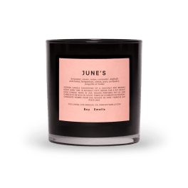 Black scented candle in a glass jar with a pink label