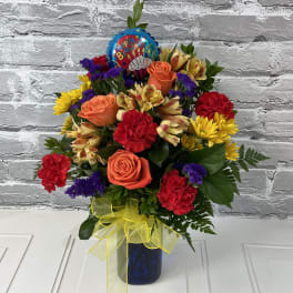 Colorful birthday bouquet in a blue vase with a balloon topper