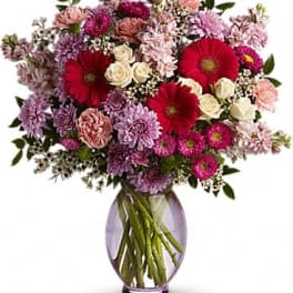 Mixed pink and red flowers in a purple glass vase