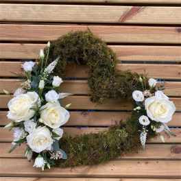 White rose floral wreath with moss on a wooden slat background