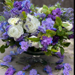 Purple and white floral arrangement in a dark vase