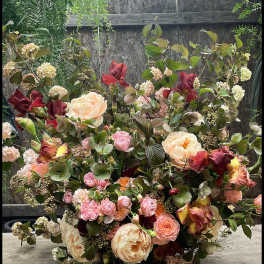 Large bouquet of peach, pink, and burgundy flowers with mixed greenery