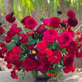 Red rose and dahlia arrangement in a dark vase