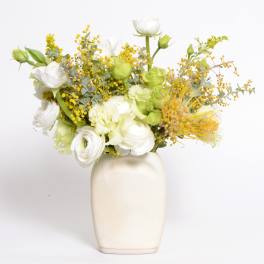 White and green floral arrangement in a cream vase