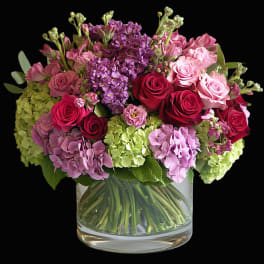 Bouquet of pink and red roses with purple hydrangeas in a glass vase