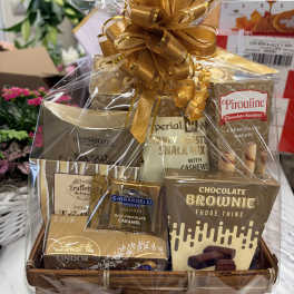 Gold-toned gourmet snack and chocolate gift basket wrapped in cellophane with a large gold bow