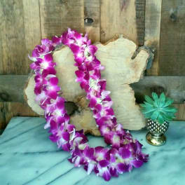 Purple orchid lei draped over a wood slab with a small potted succulent