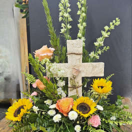 Cross-shaped floral arrangement with sunflowers, peach roses, and white blooms