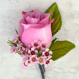 Pink rose boutonniere with small pink blossoms and green leaves