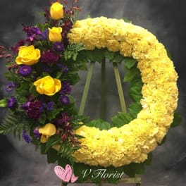 Circular floral wreath with yellow flowers and purple roses on an easel