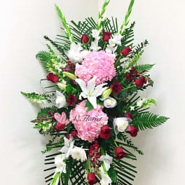 Standing floral spray with pink hydrangeas, red roses, and white lilies