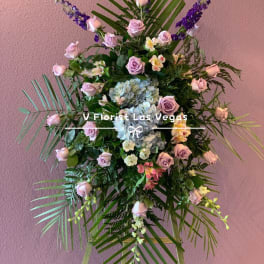 Standing floral spray with pink roses, blue hydrangea, and purple accents