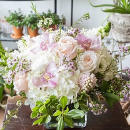 Pink roses and white hydrangeas in a glass vase with small accent flowers