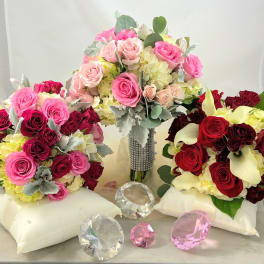 Three rose bouquets with calla lilies and hydrangeas on satin pillows