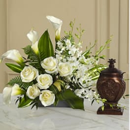 White roses and calla lilies arranged with white orchids in a low container