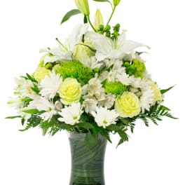 White lilies and daisies in a glass vase with green accents