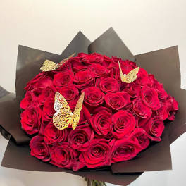 Bouquet of red roses wrapped in dark paper with gold butterfly accents