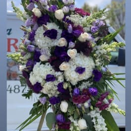 Tall purple and white floral standing spray on an easel