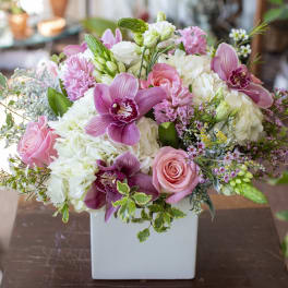 Pink and white floral arrangement in a white square vase
