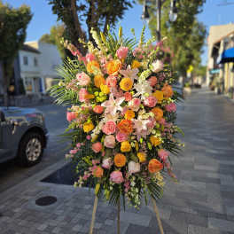 Large standing floral spray with pink, orange, and yellow blooms on an easel