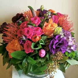 Colorful bouquet of roses, hydrangea, and tropical blooms in a glass vase