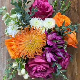 Bouquet of orange, magenta, and white flowers with eucalyptus foliage