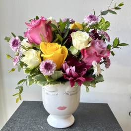 Mixed roses and daisies in a white face vase
