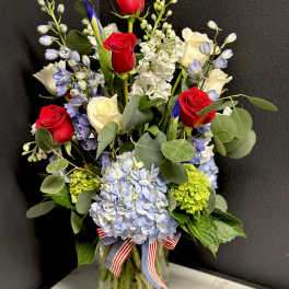 Bouquet of red and white roses with blue flowers in a glass vase