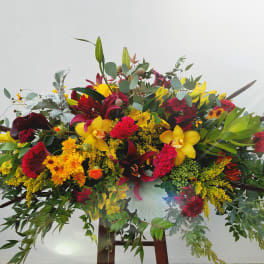 Large colorful floral arrangement with yellow, red, and burgundy blooms