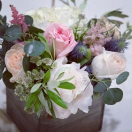 Bouquet of pink and white roses with purple thistle in a brown wrap