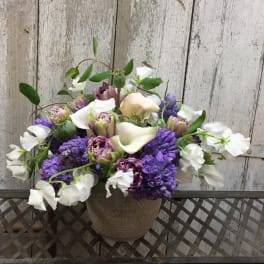 Purple and white floral arrangement in a textured vase