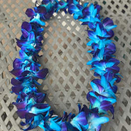 Blue and purple flower lei on a woven chair