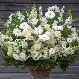 White floral arrangement in a woven basket on a pedestal
