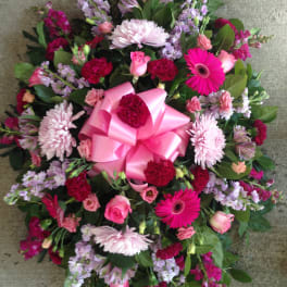 Round bouquet of pink and purple flowers with a large pink bow