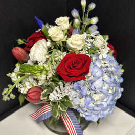 Bouquet of red and white roses with blue hydrangea in a glass vase