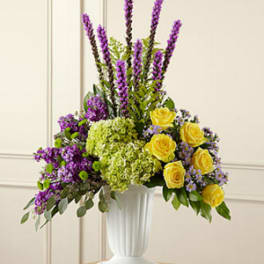 Purple and yellow floral arrangement in a white vase