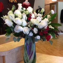 Large bouquet of white and red flowers in a tall glass vase