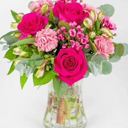 Pink roses and carnations arranged in a clear glass vase