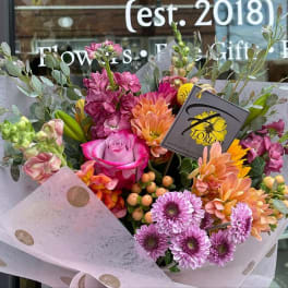 Mixed bouquet with pink roses, orange dahlias, and purple daisies in polka-dot wrap