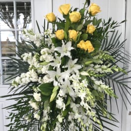 Large standing spray of yellow roses and white lilies with orchids