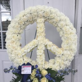 White floral peace sign standing spray with blue and cream flowers at the base