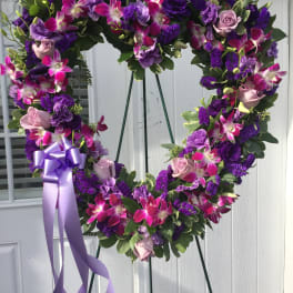 Heart-shaped floral wreath with purple and pink flowers on an easel