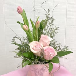 Pink tulips and roses arranged in a pink butterfly tin