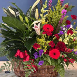 Mixed flower arrangement in a wicker basket with red and white blooms